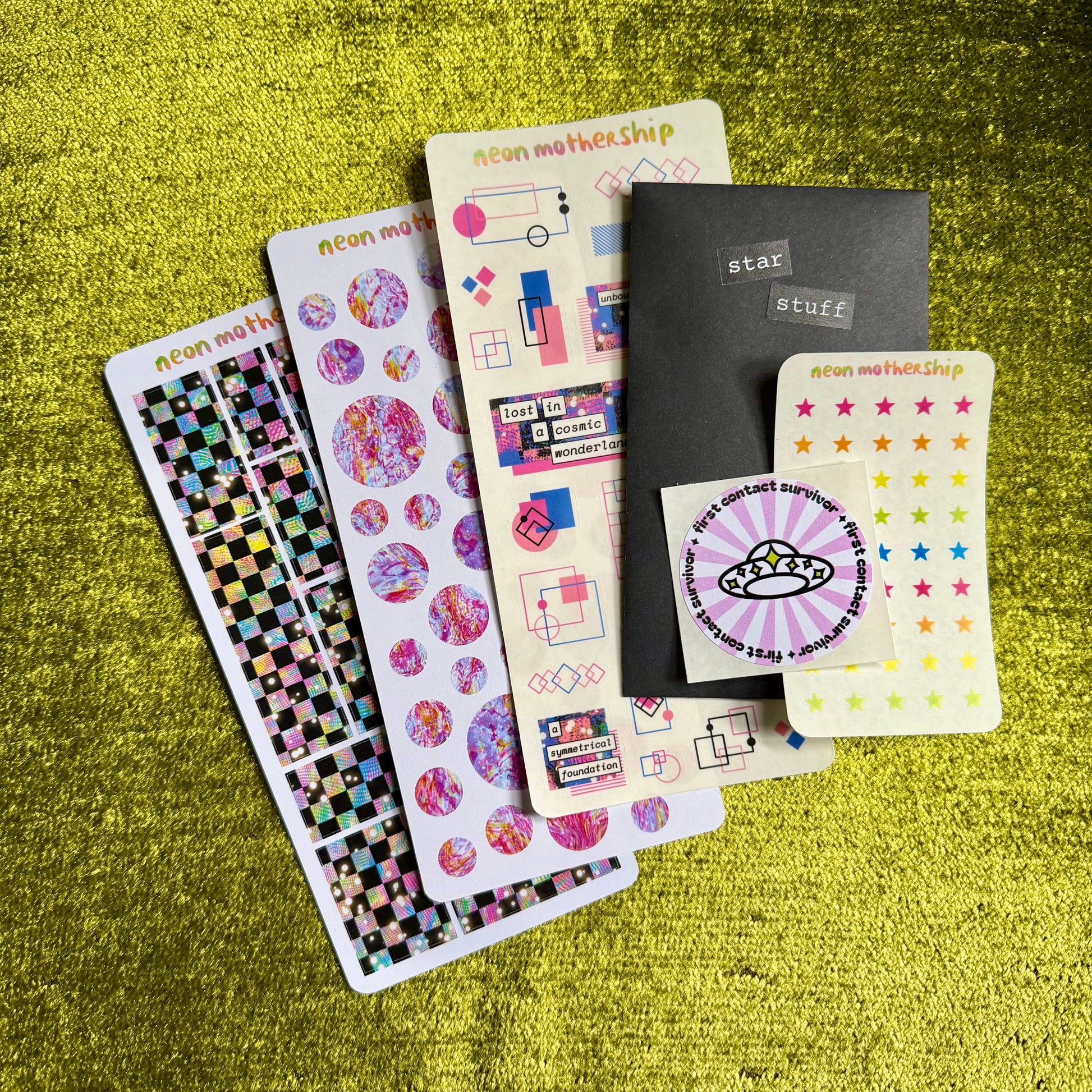 Collection of colorful sticker sheets and on a green textured surface