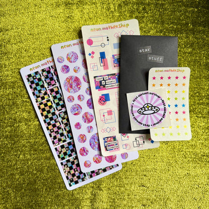 Collection of colorful sticker sheets and on a green textured surface