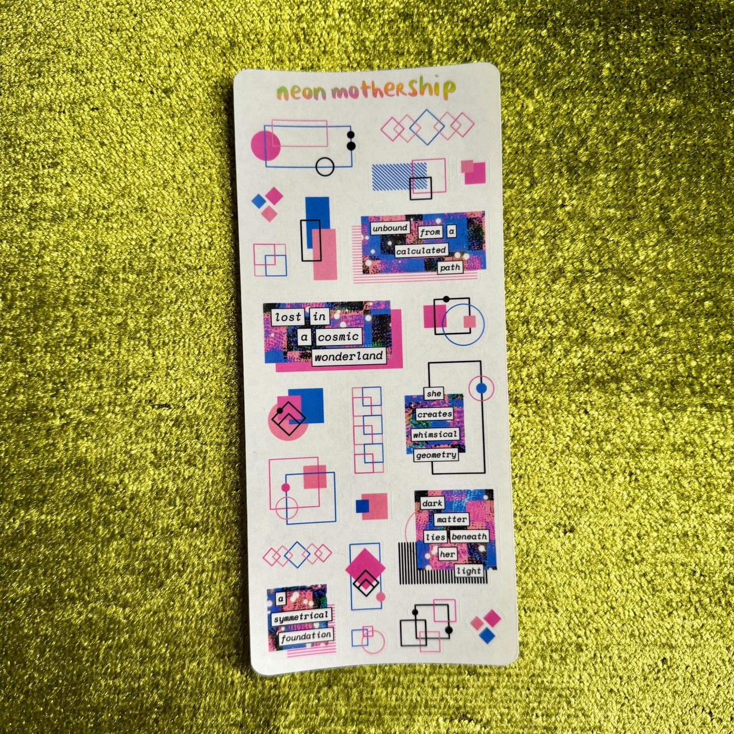 Sheet of colorful stickers with geometric designs on a green textured surface