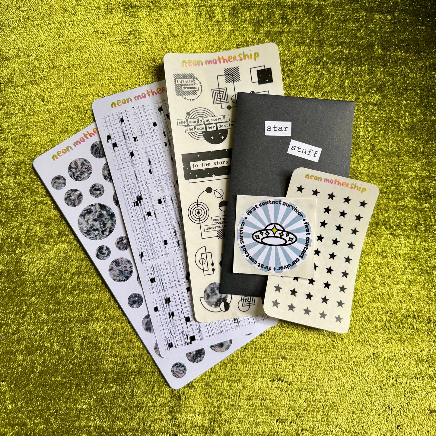 Collection of sticker sheets on a green textured surface