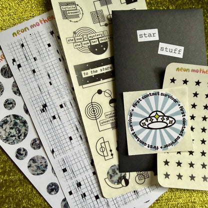 Collection of stationery items including sticker sheets on a textured green surface