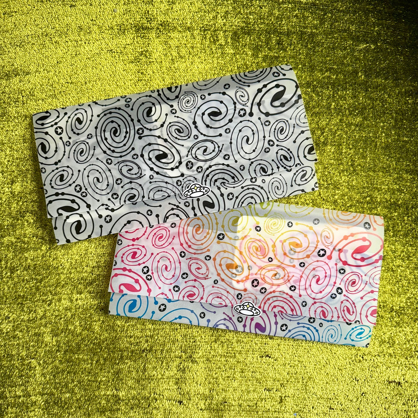 Two patterned vellum paper envelopes on a textured green surface