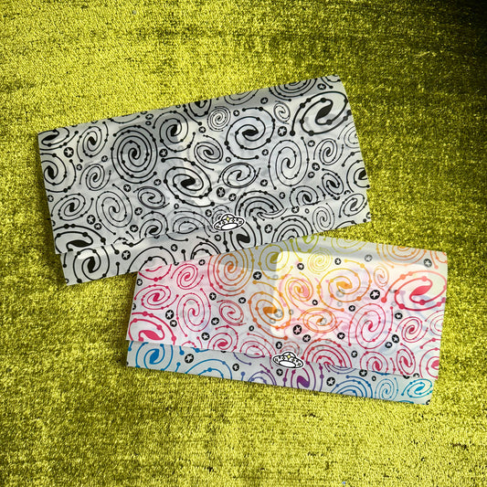 Two patterned vellum paper envelopes on a textured green surface