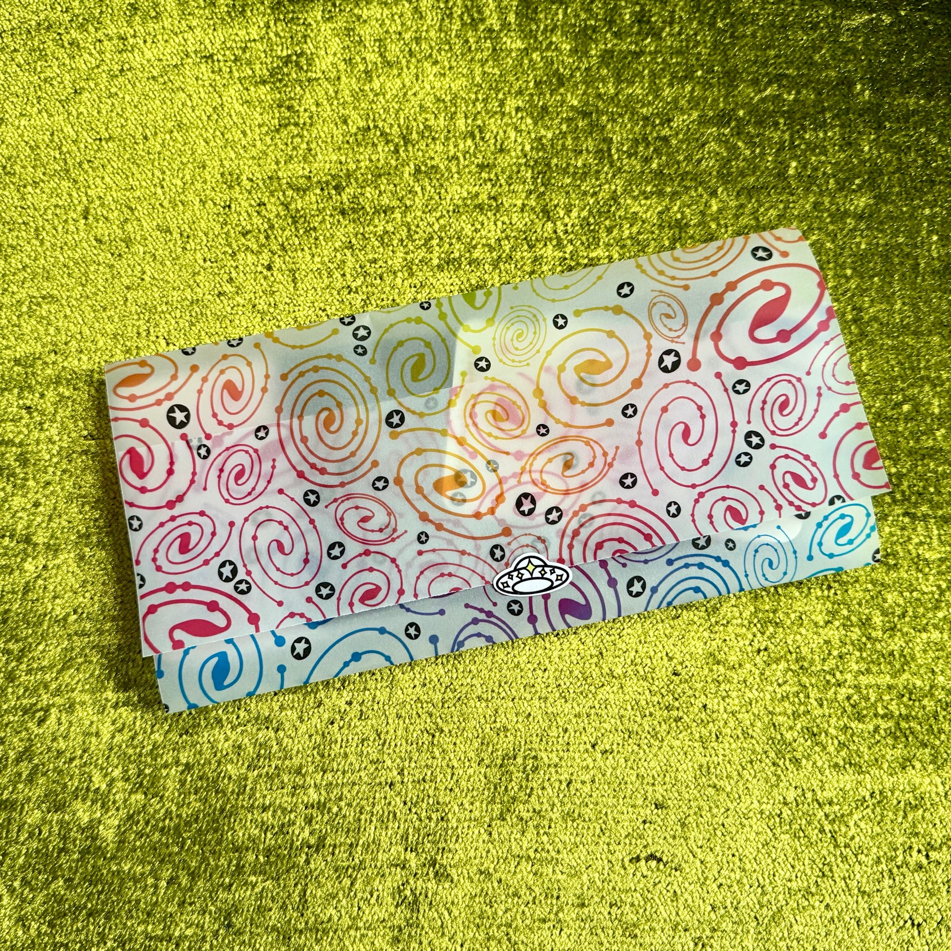 Colorful patterned vellum envelope on a textured green surface