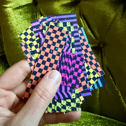 hand holding small collection of colorful sticker scraps against a green background