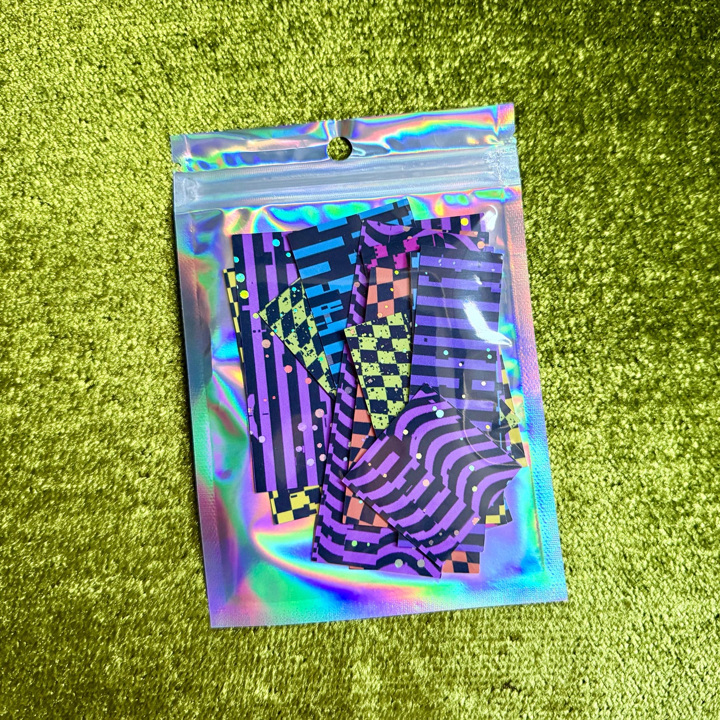 small holographic bag with colorful sticker scraps on a green background