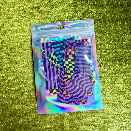 small holographic bag with colorful sticker scraps on a green background