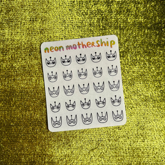 Sheet of stickers with black and white designs on a green textured surface