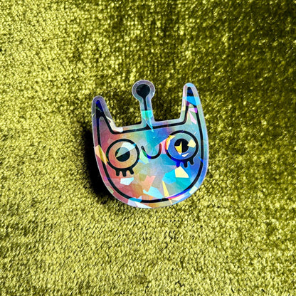 Holographic cat-shaped sticker on a green textured background