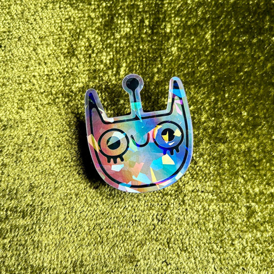 Holographic cat-shaped sticker on a green textured background