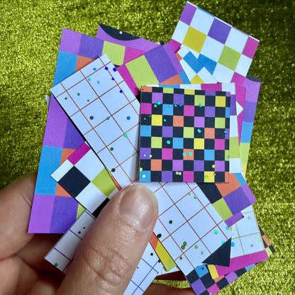 hand holding a set of colorful sticker scraps on a green background