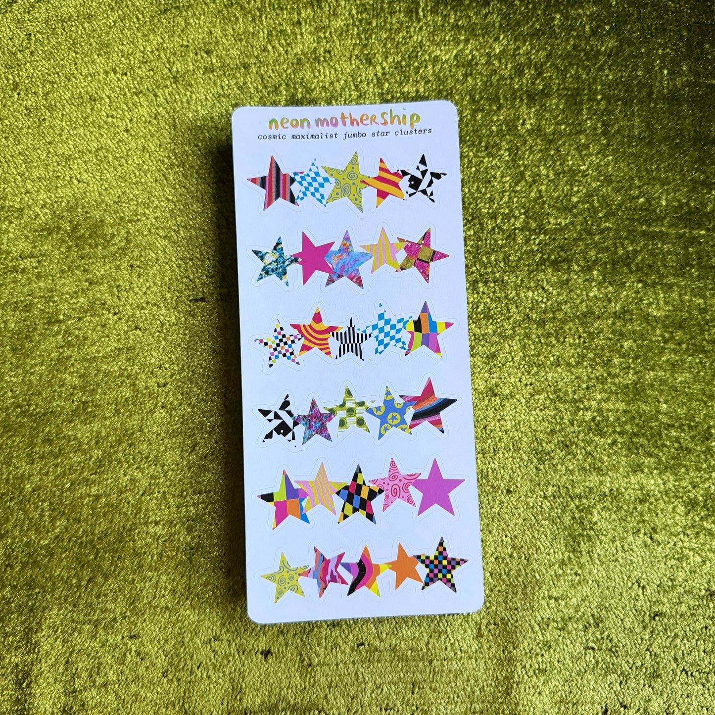 white sticker sheet with colorful star-shaped stickers on a green textured surface