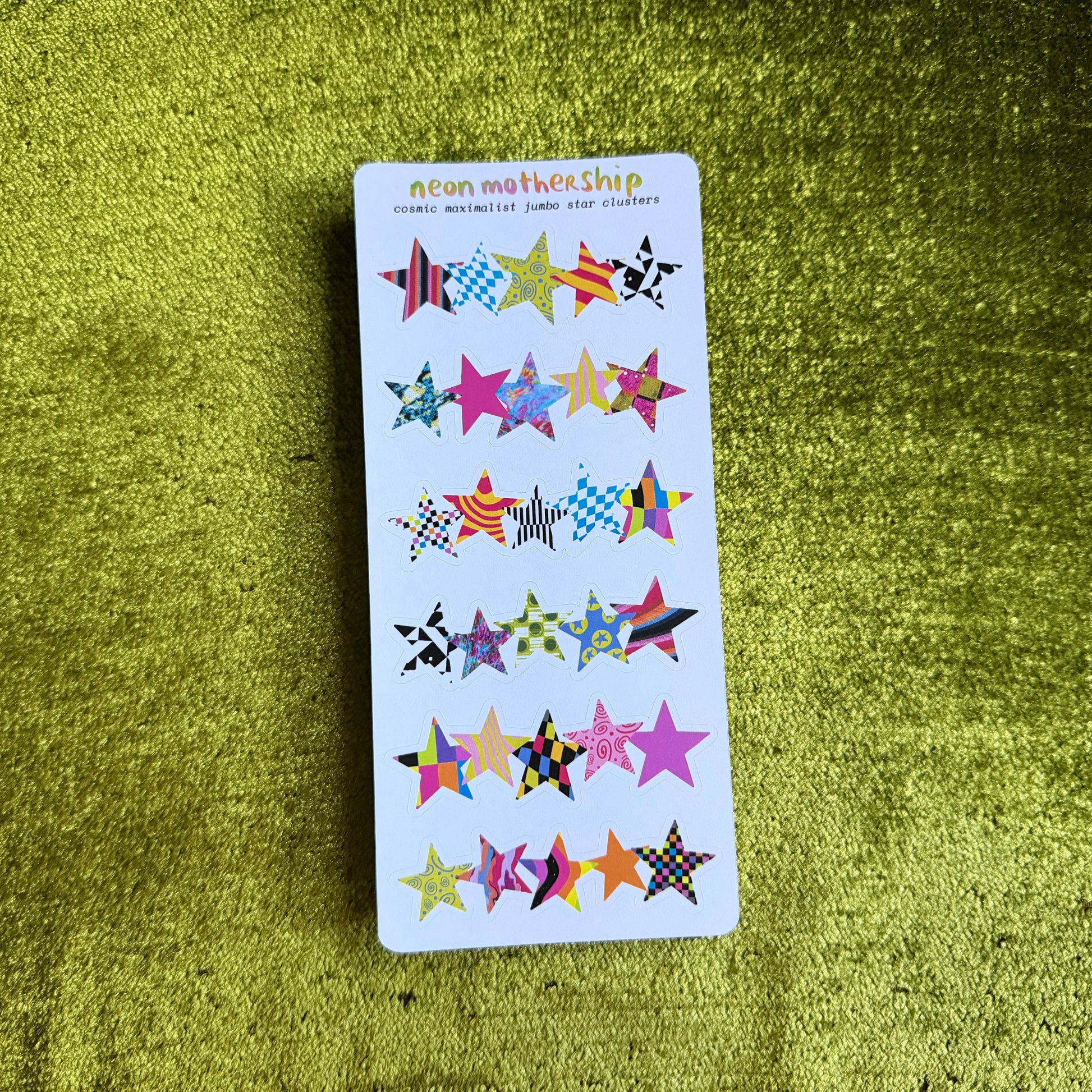 white sticker sheet with colorful star-shaped stickers on a green textured surface