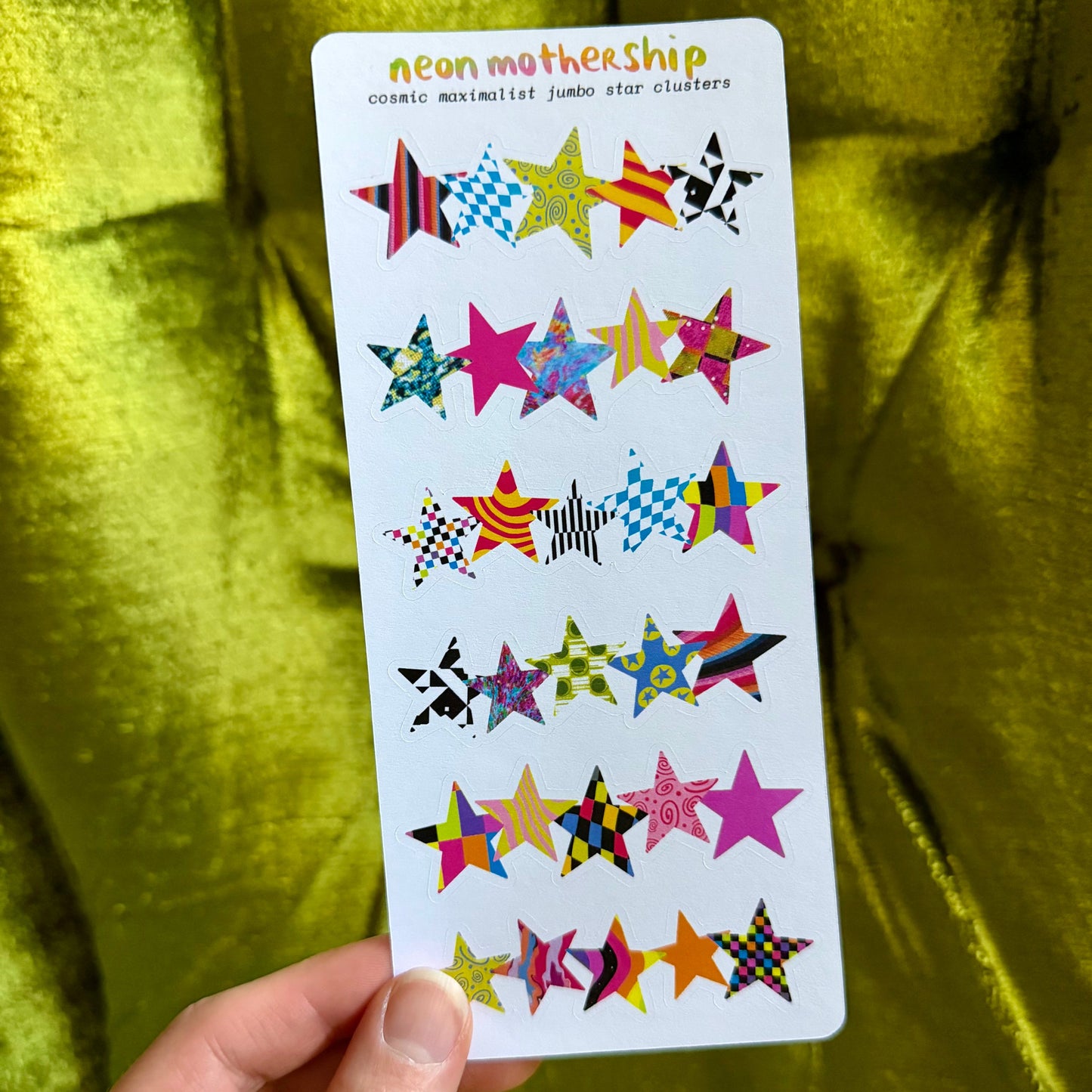 sticker sheet with colorful star-shaped stickers held against a green fabric background