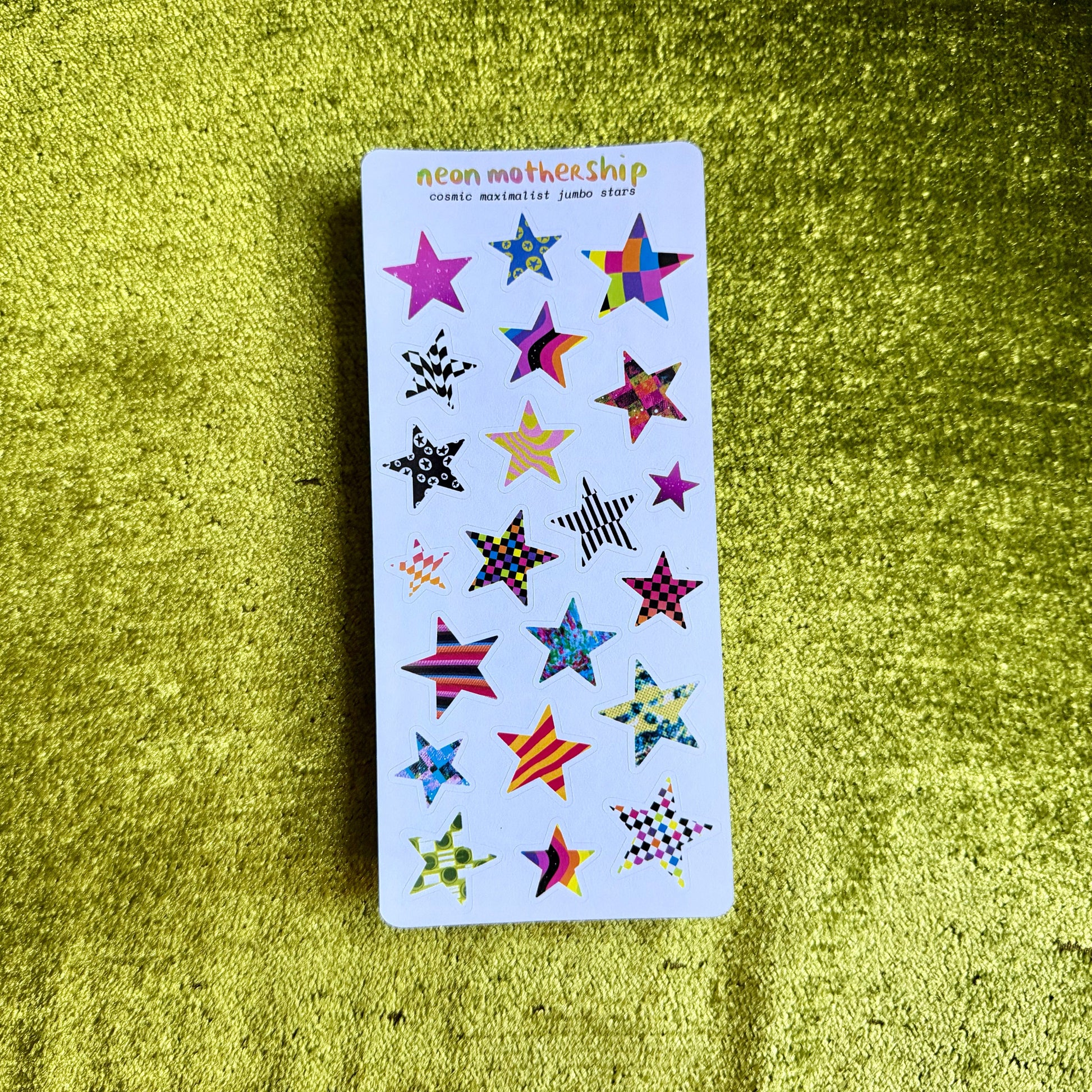 Sticker sheet with colorful star designs on a green textured surface