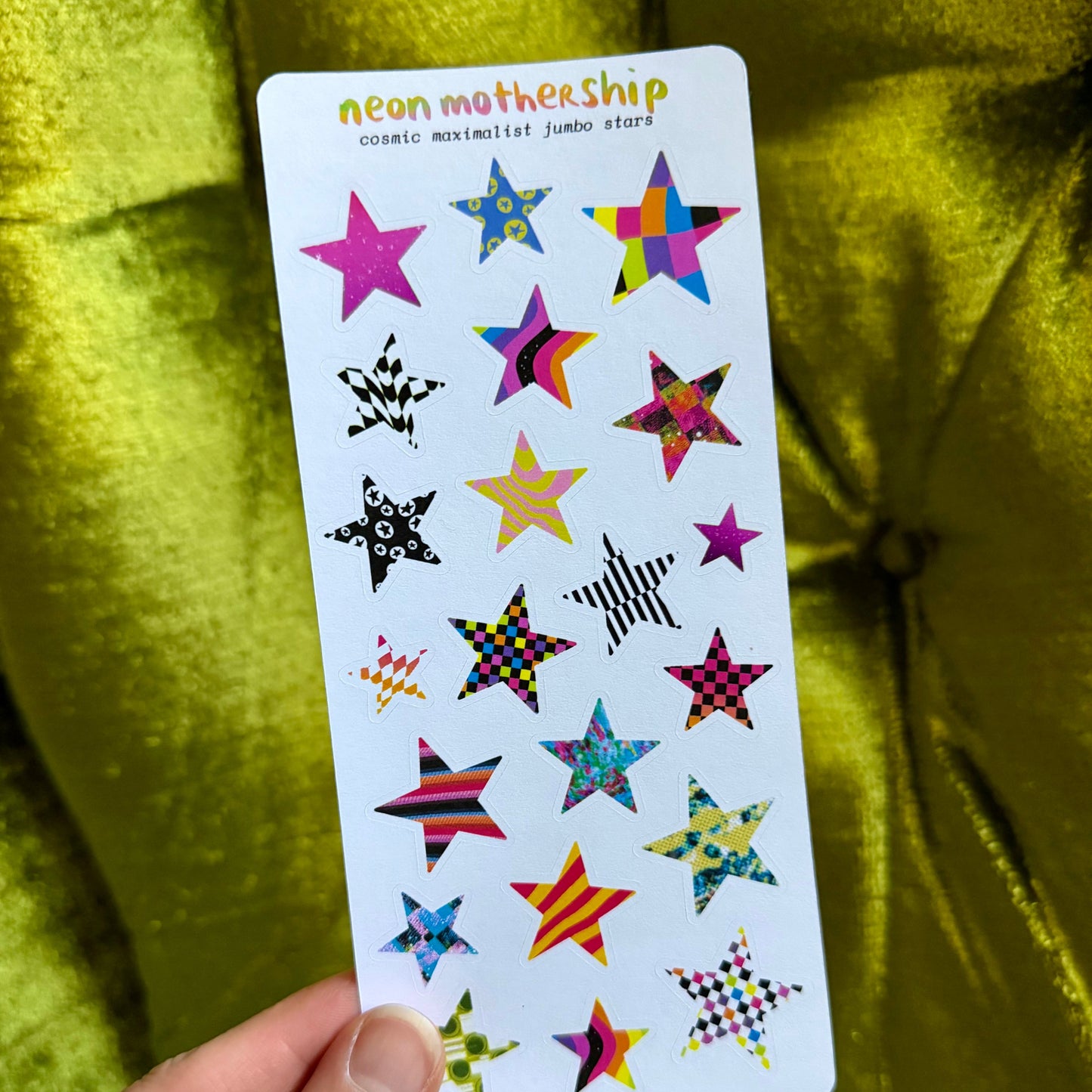 Card with colorful star-shaped stickers held against a green fabric background