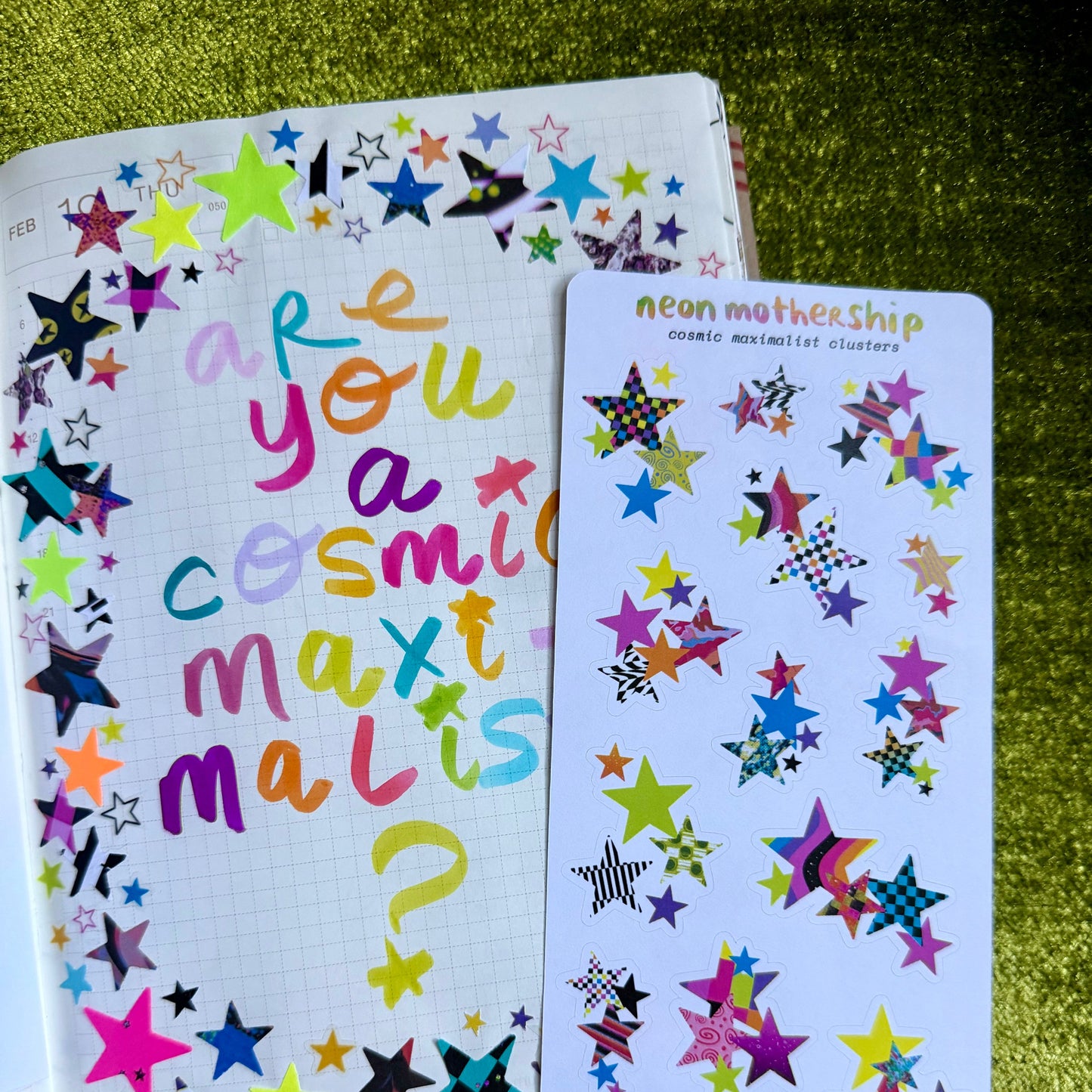 Colorful star-patterned notebook and stickers on a green textured surface