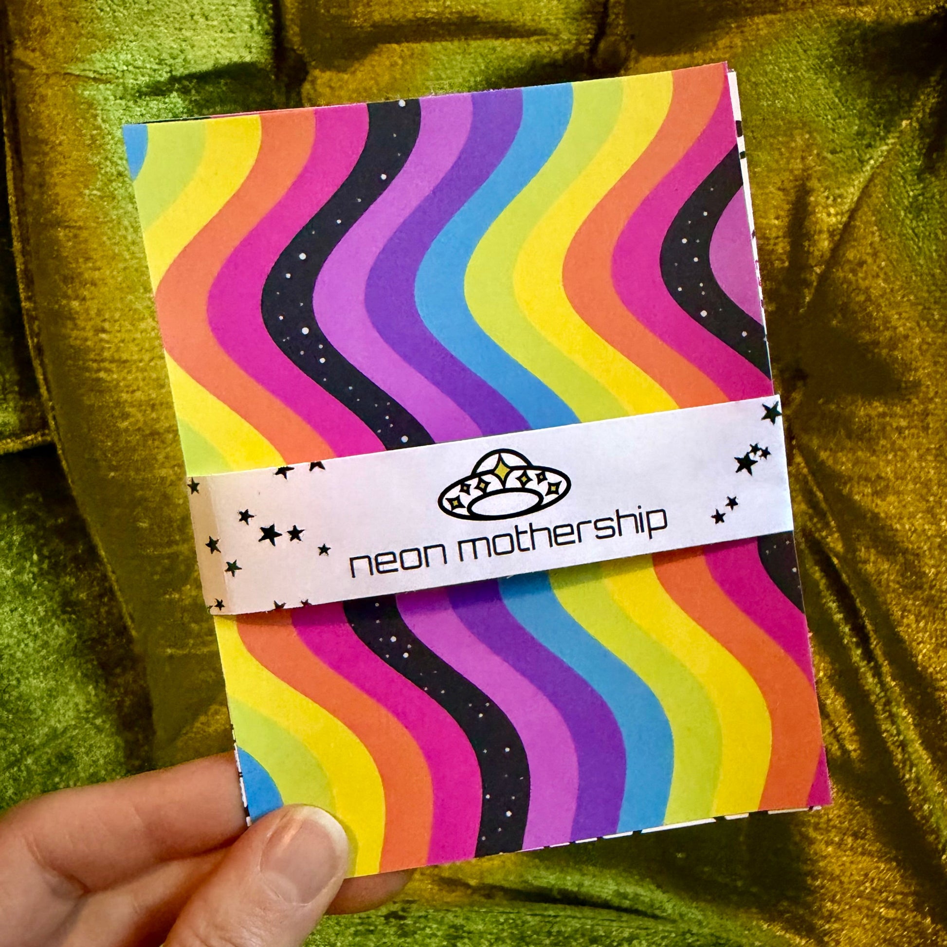 hand holding colorful sticker paper on a green background