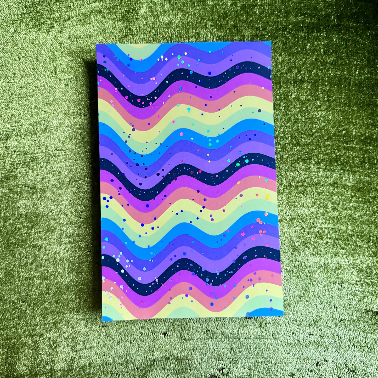rainbow sticker paper on a green background with holographic sparkles