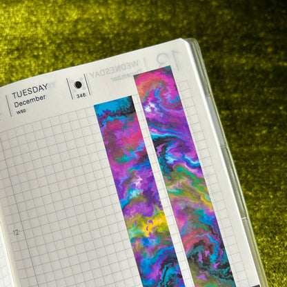 Open notebook with colorful watercolor sticker strips on a green textured surface