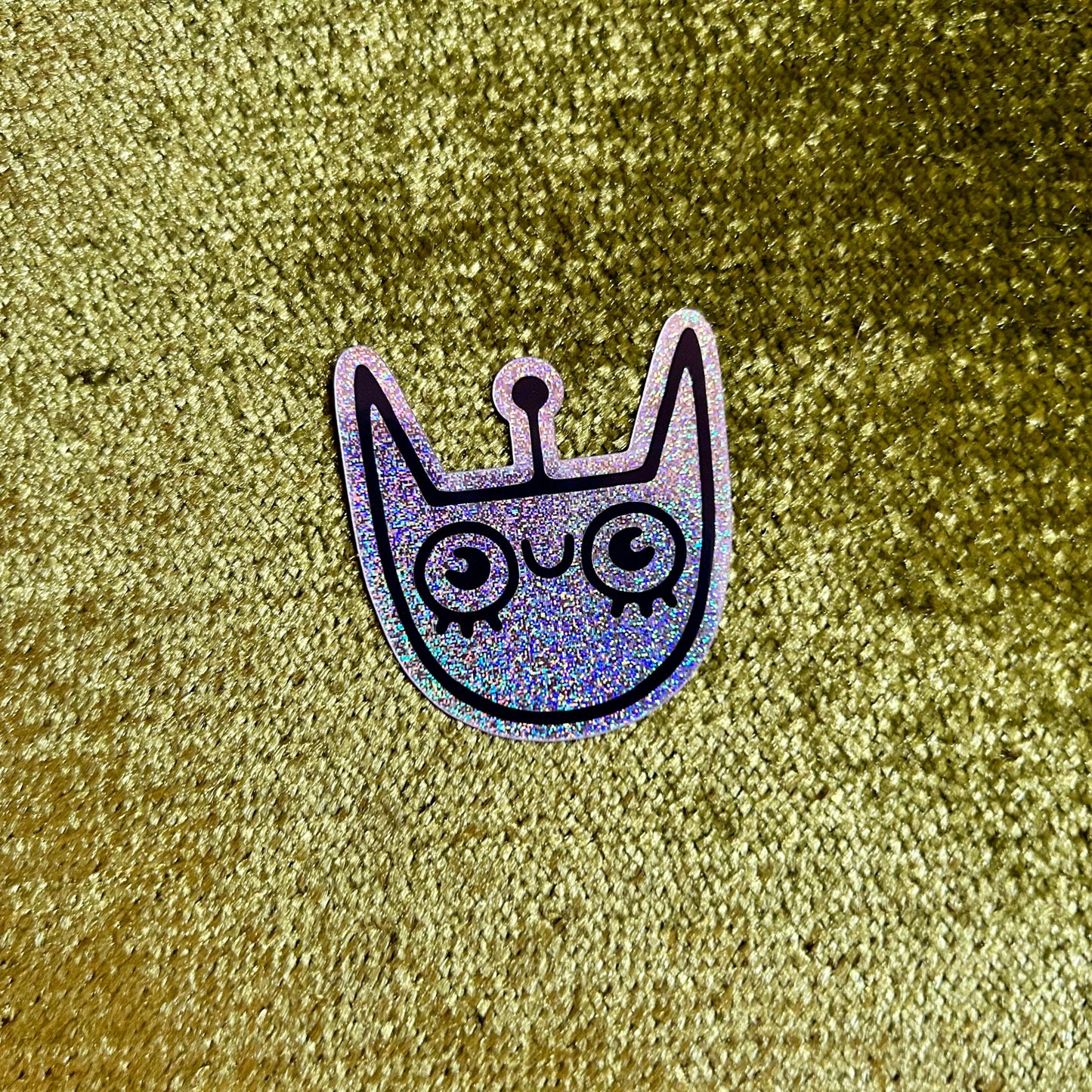 Holographic cat-shaped sticker on a textured gold background