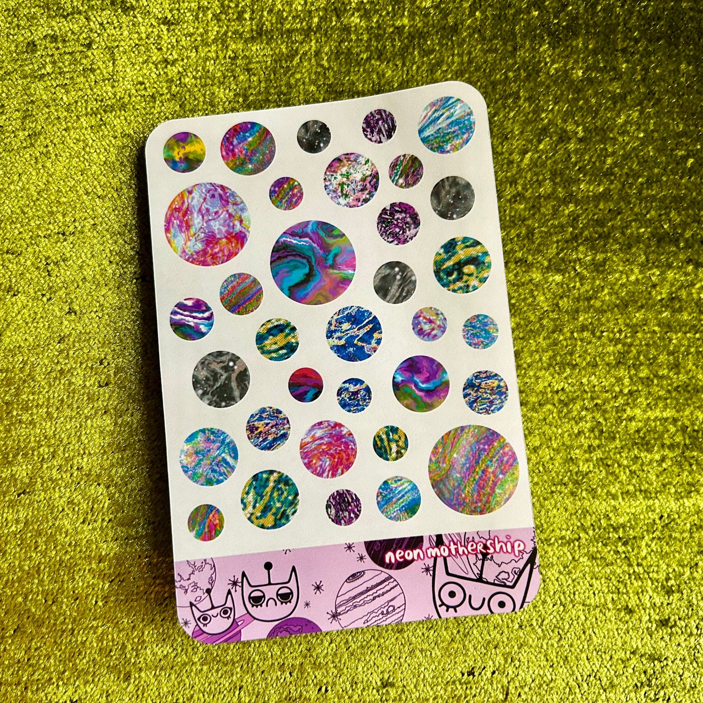 Sticker sheet with colorful designs on a green textured surface