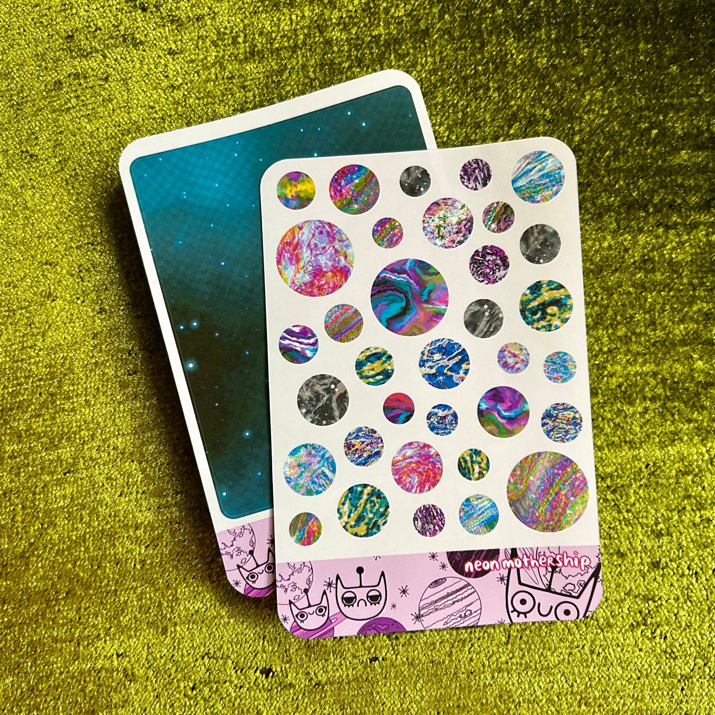Sticker sheet with colorful designs on a textured green surface