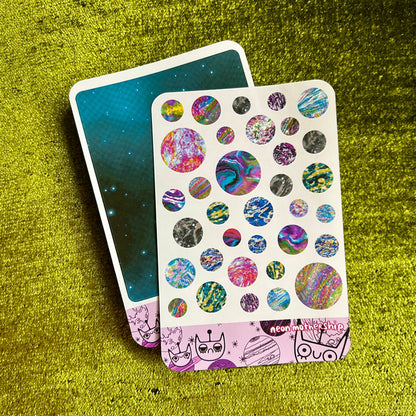 Sticker sheet with colorful designs on a textured green surface