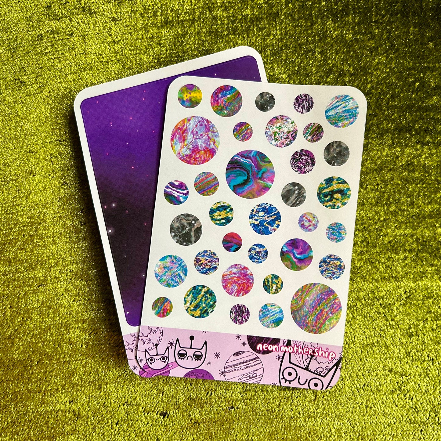 Sticker sheet with colorful planet designs on a green textured surface