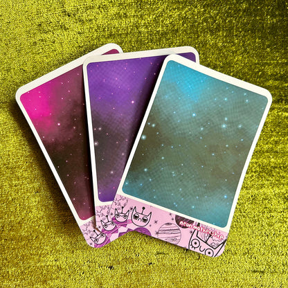 Three playing cards with space-themed designs on a green textured surface
