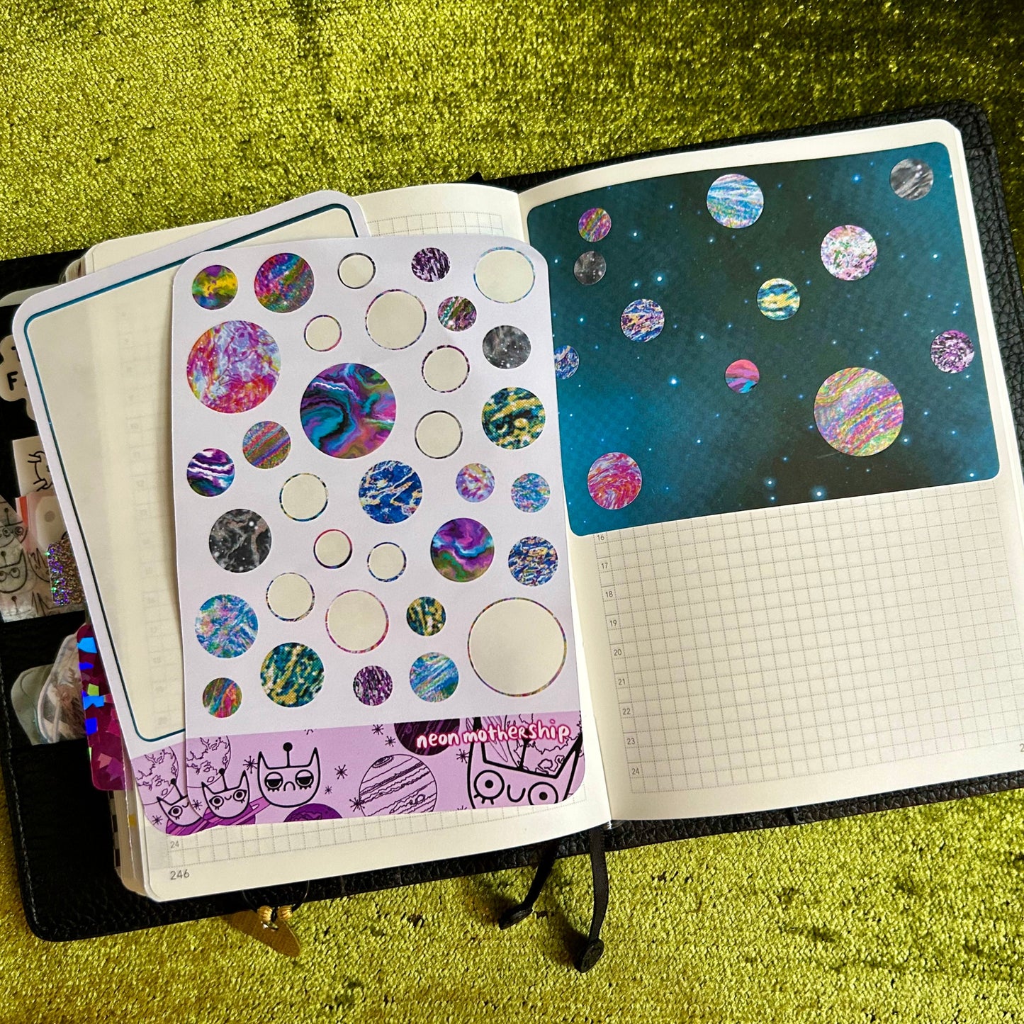Open notebook with stickers on a green textured surface