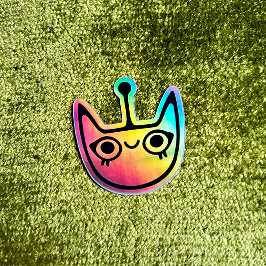 Colorful alien cat sticker on a green textured surface