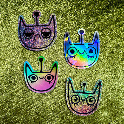 Four colorful space cat shaped stickers on a green glittery background