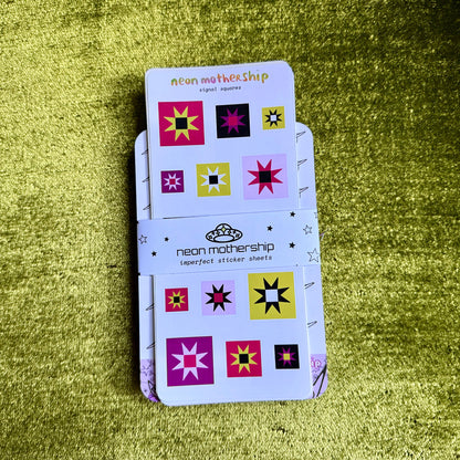 A stack of 'neon mothership' imperfect sticker sheets held together by a branded paper band, displayed on a textured olive green background.