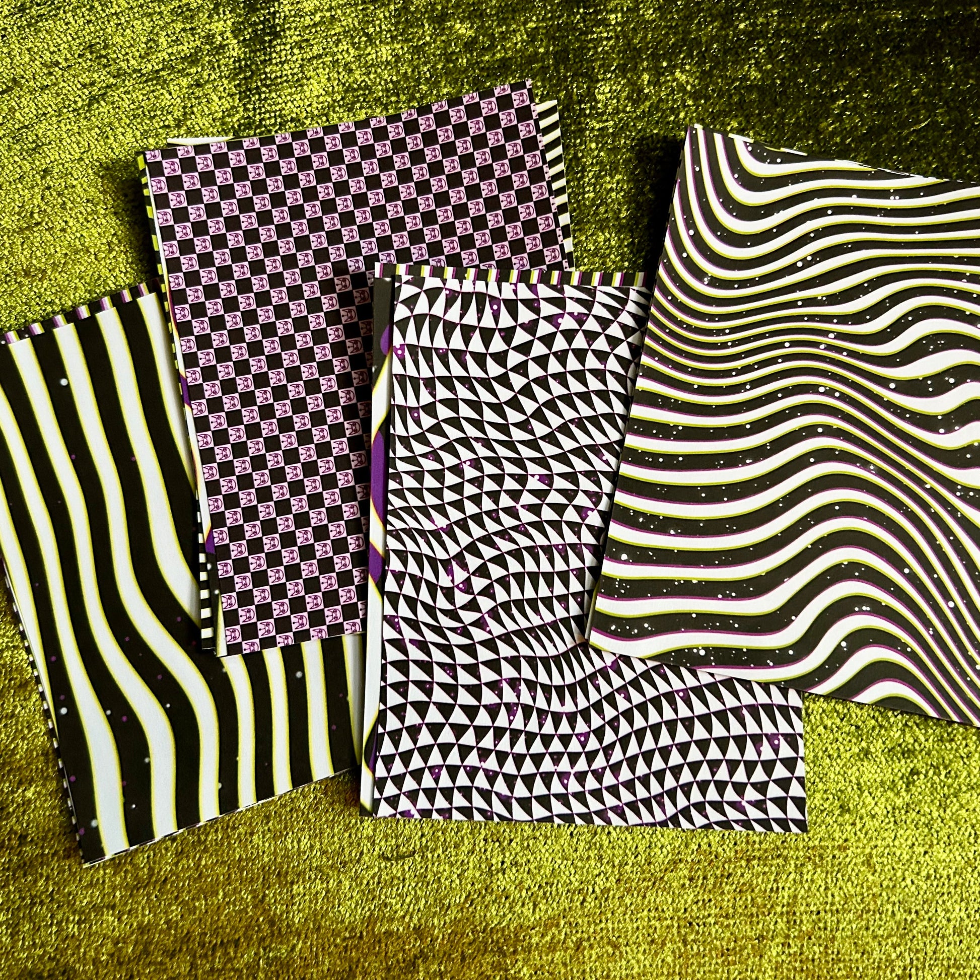 Four stacks of sticker sheets with different patterns on a textured green surface