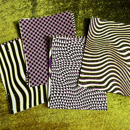 Four stacks of sticker sheets with different patterns on a textured green surface