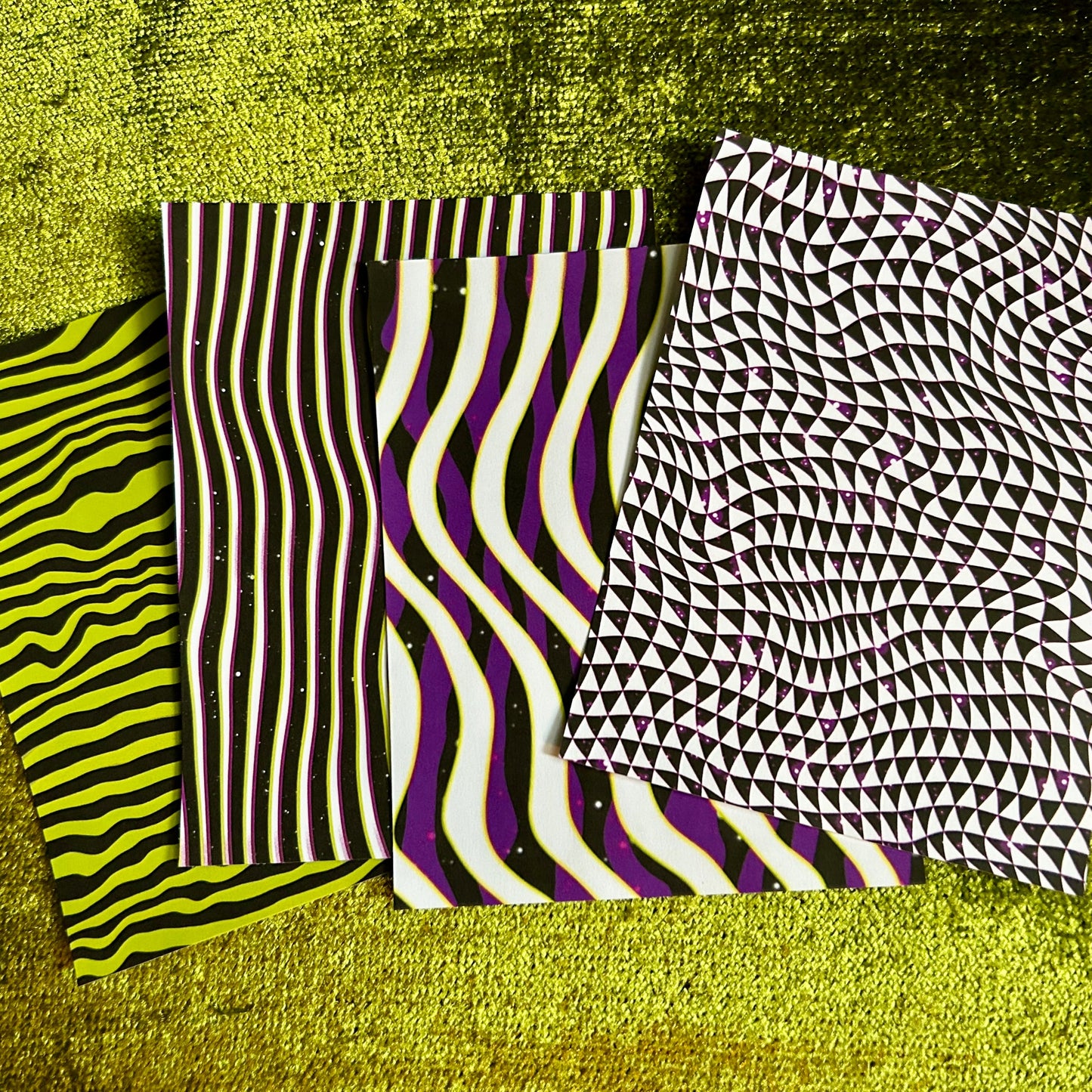 Four sticker scrap sheet samples with different patterns on a textured green surface