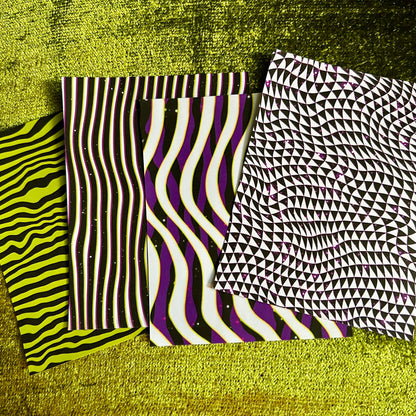 Four sticker scrap sheet samples with different patterns on a textured green surface