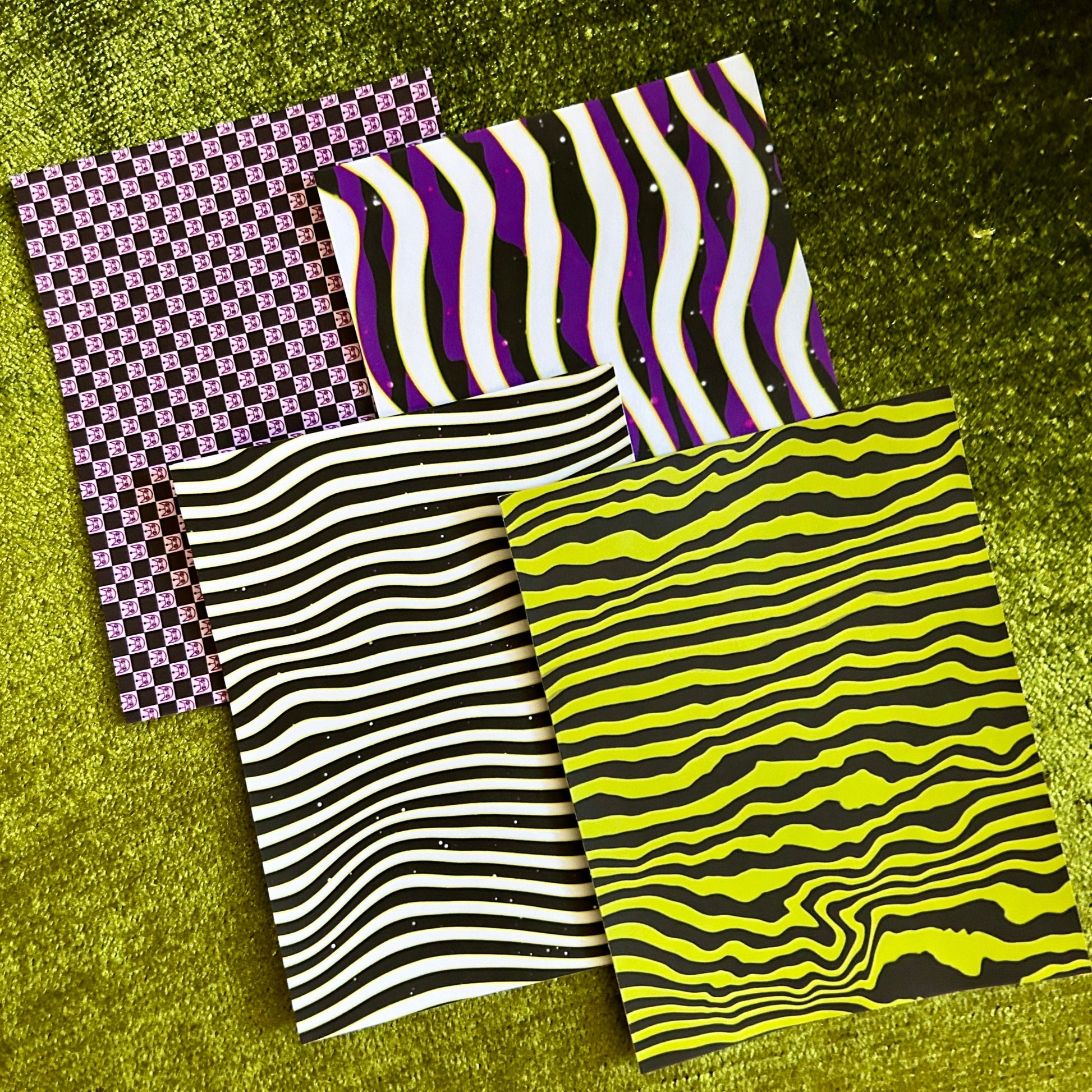Four pieces of patterned sticker paper on a green textured surface