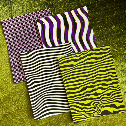 Four pieces of patterned sticker paper on a green textured surface