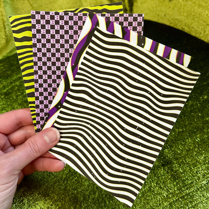 Hand holding a black and white striped sticker paper with a checkered pattern in the background