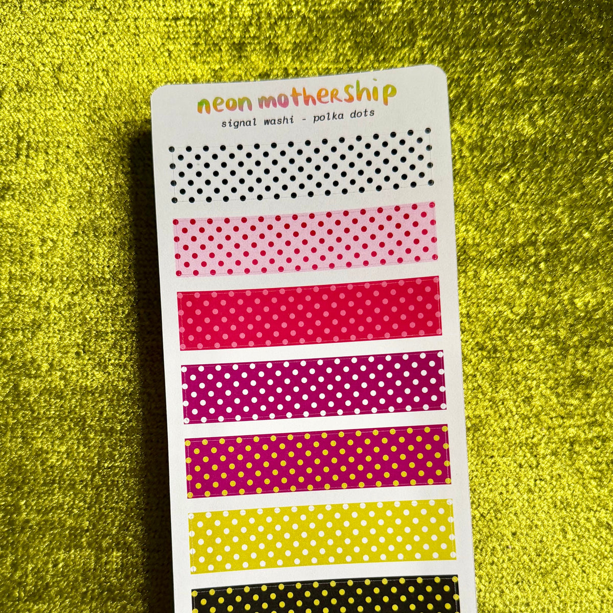A sticker sheet from the brand 'neon mothership' featuring eight horizontal strips of washi tape patterns in black, pink, and yellow on a textured yellow background.