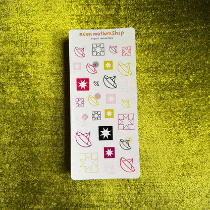 A rectangular sticker sheet from neon mothership called 'Detectors' featuring various colorful geometric and abstract shapes, placed on a textured green background.