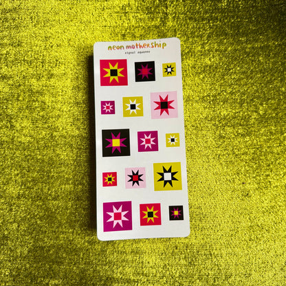 A sticker sheet titled 'neon mothership' featuring twelve colorful geometric starburst stickers in pink, yellow, black, and white, displayed on a textured, shiny gold green background.