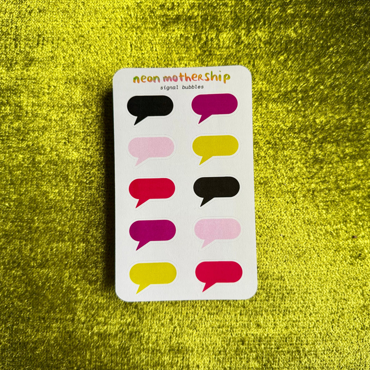 A white sticker sheet of neon mothership speech bubbles with 12 colorful sticker bubbles in shades of pink, yellow, red, and black, displayed on a textured yellow background.