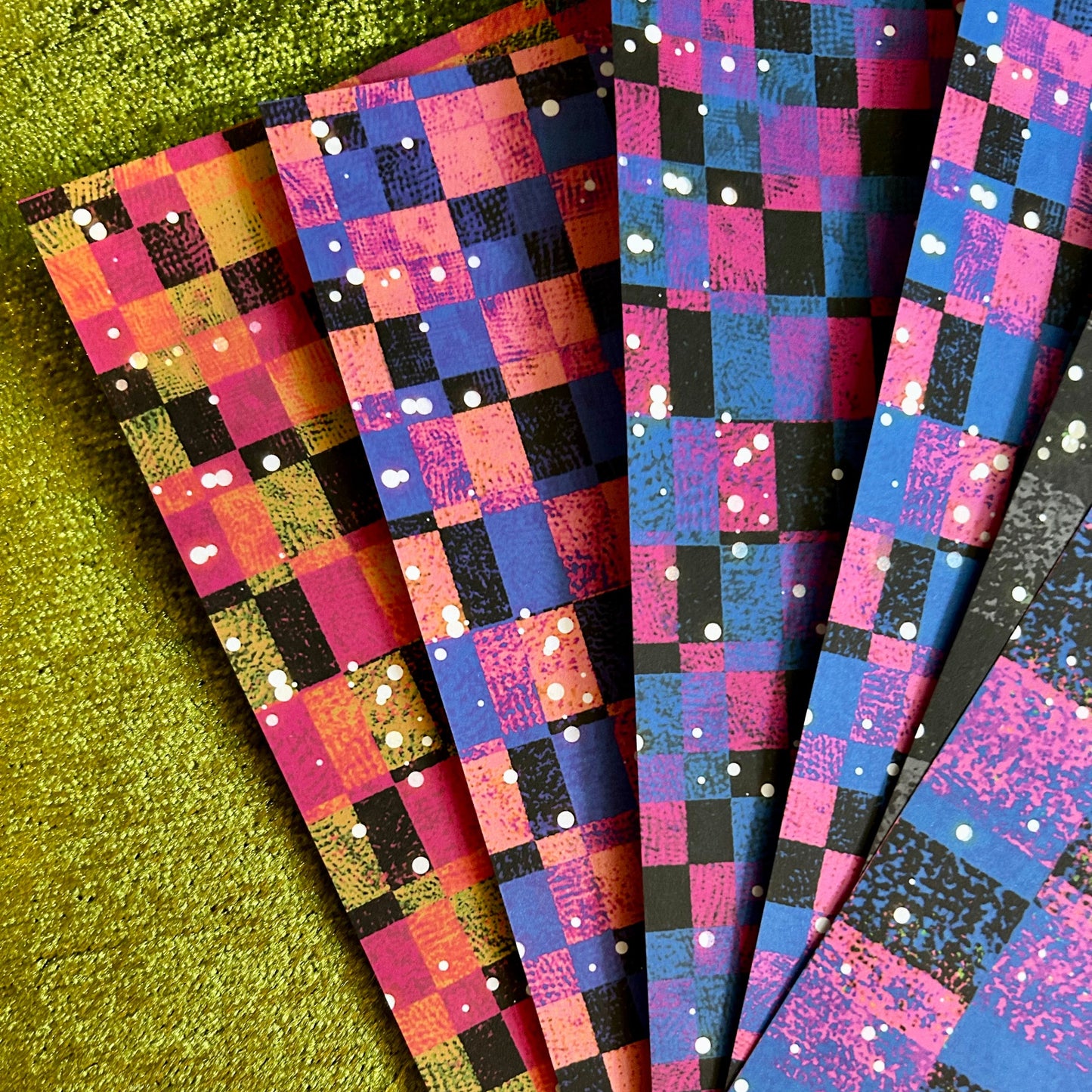 Colorful checkered paper sheets on a green surface