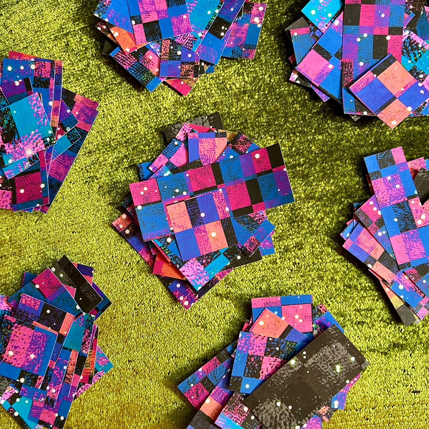 Colorful geometric sticker scraps scattered on a green surface