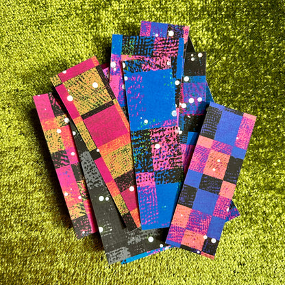 Colorful checkered sticker scraps stacked on a green textured surface