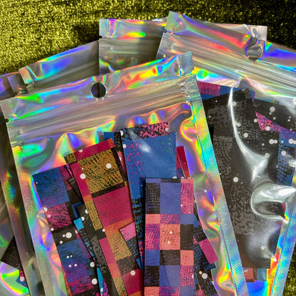 Holographic bags with colorful stickers on a green textured background
