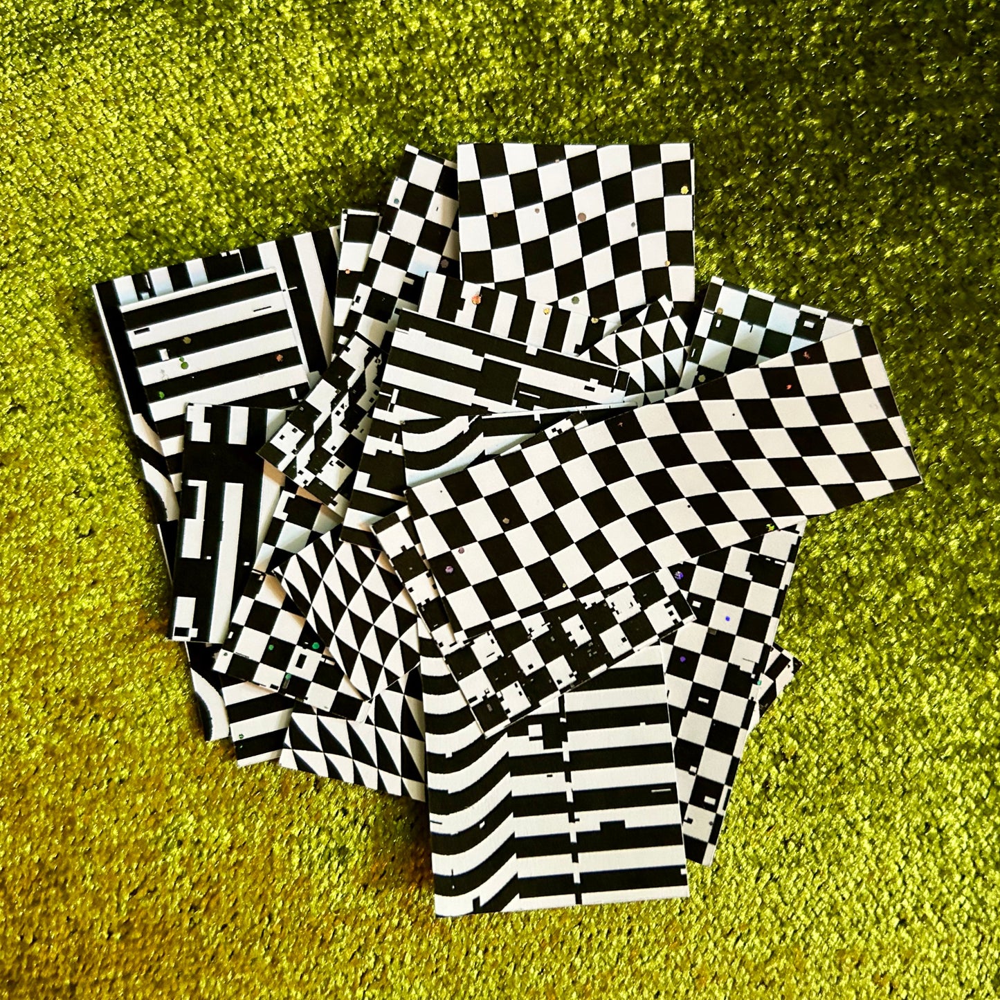Black and white checkered and striped sticker pieces on a green textured surface